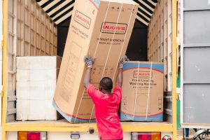 Two movers in blue uniforms carry furniture up a staircase during a professional relocation in Westlands.