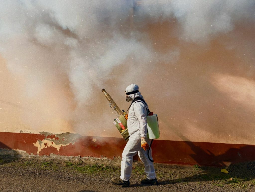 Team fumigating a residential room with fog machine for pest control.