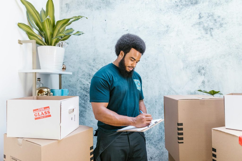 Professional office movers carefully lifting a large desk through a doorway.
